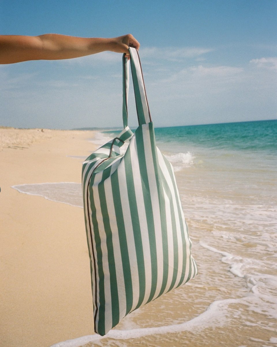 Tribeca backrest held by its strap in one hand at the shoreline