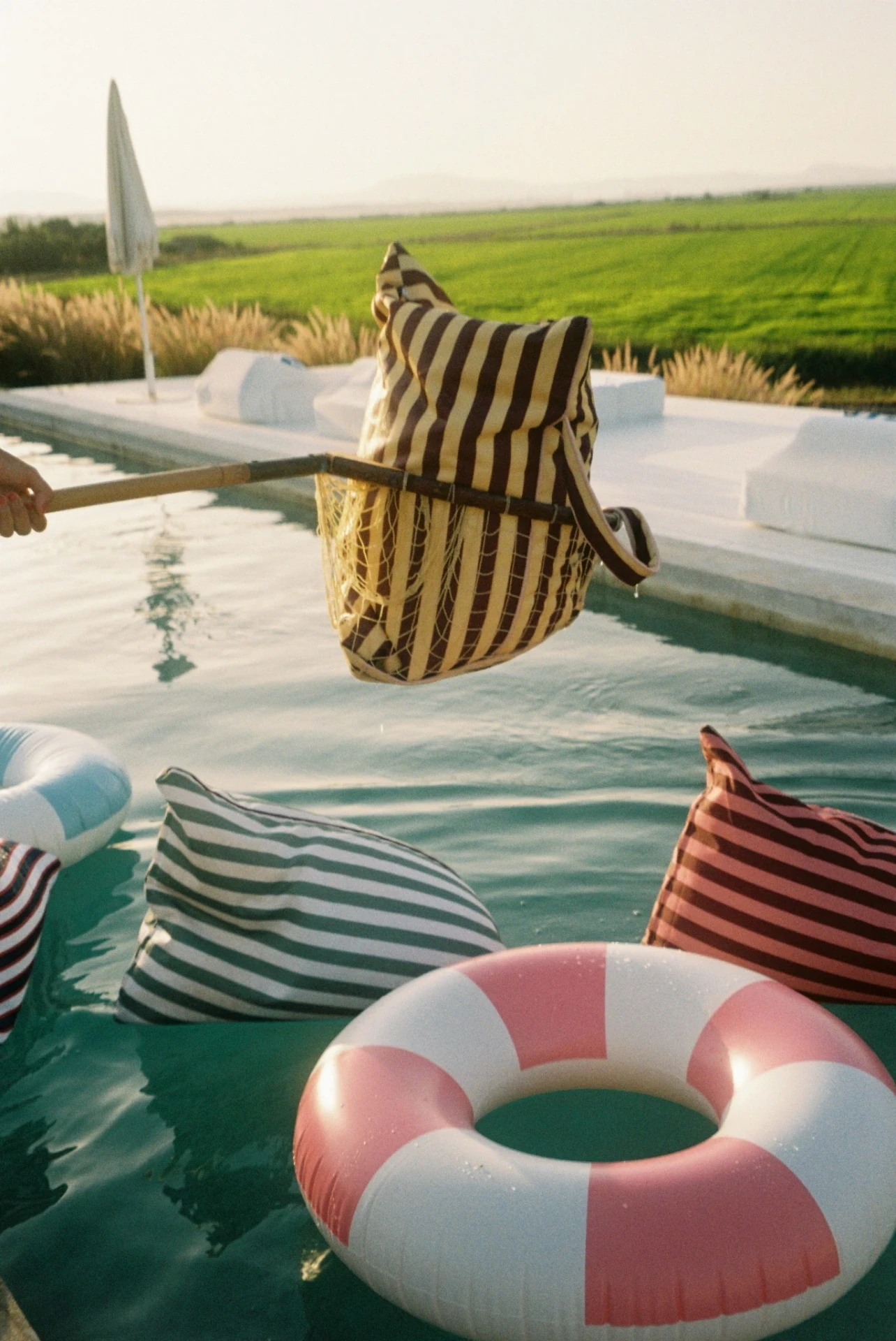 Striped LIELOW bag held above a swimming pool