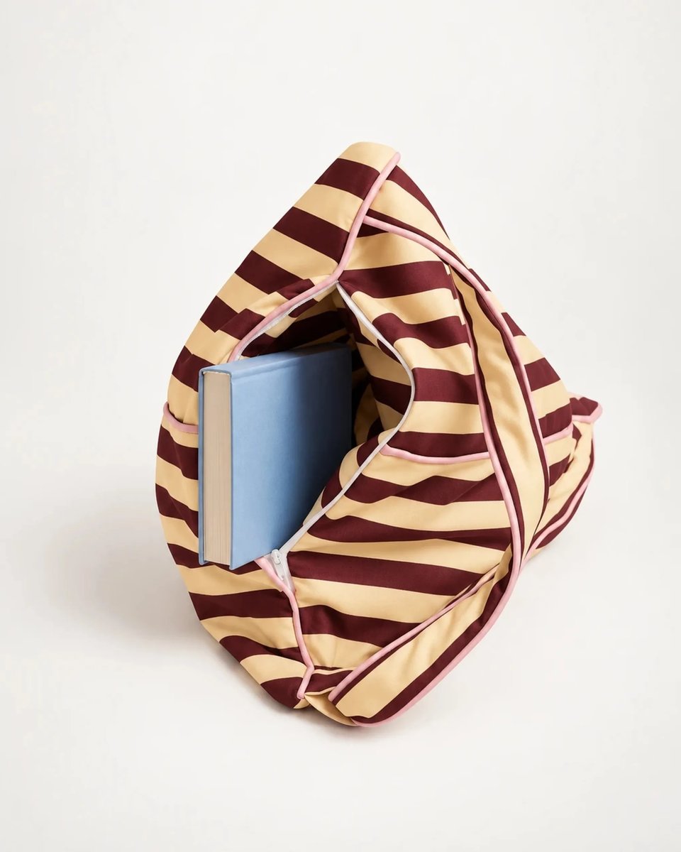 Open storage compartment of the Pier 55 backrest holding a hardcover book