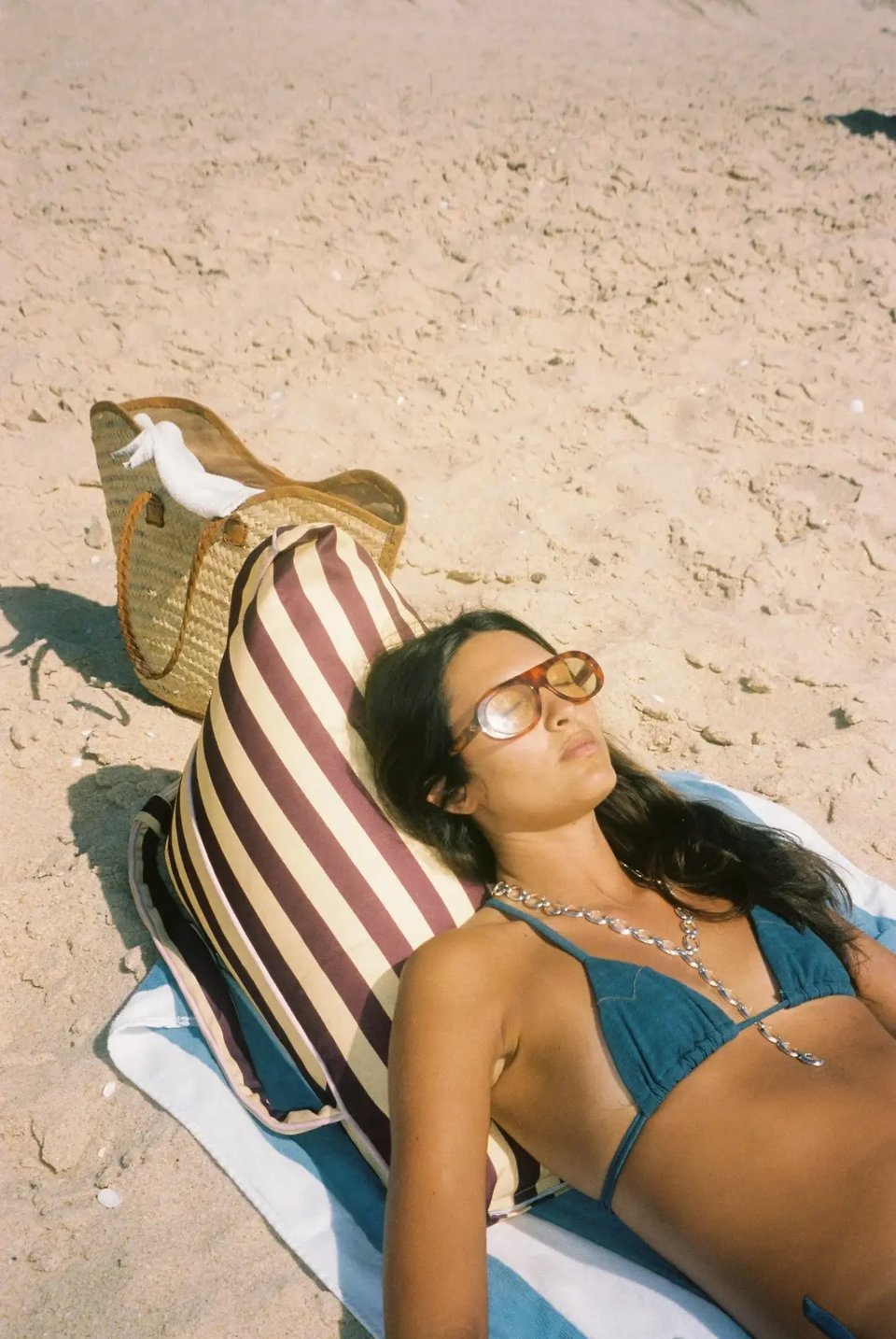 Woman leaning back against the Pier 55 backrest on the beach, reading