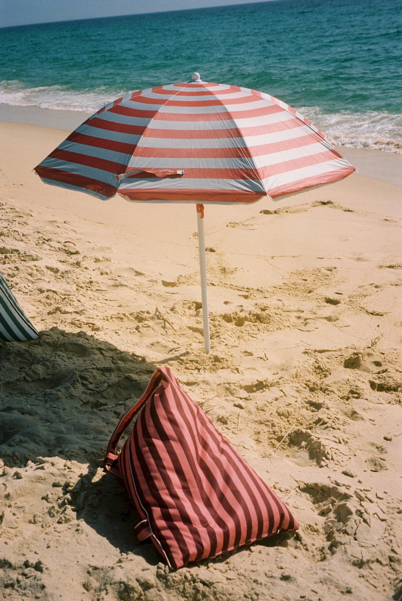 Lielow East Hampton — berry striped bag-chair on the sand beneath a beach umbrella