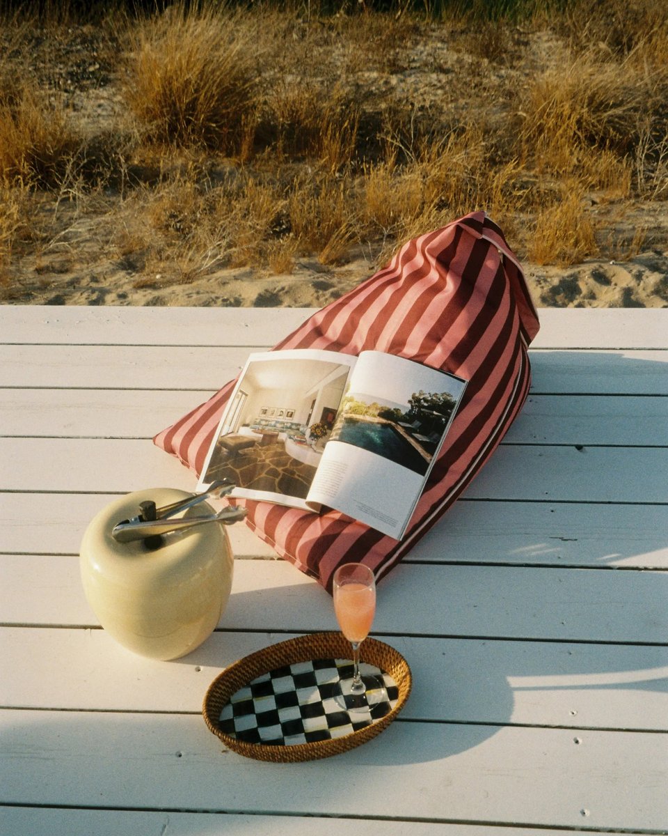 East Hampton backrest on a white deck with an open magazine and a drink