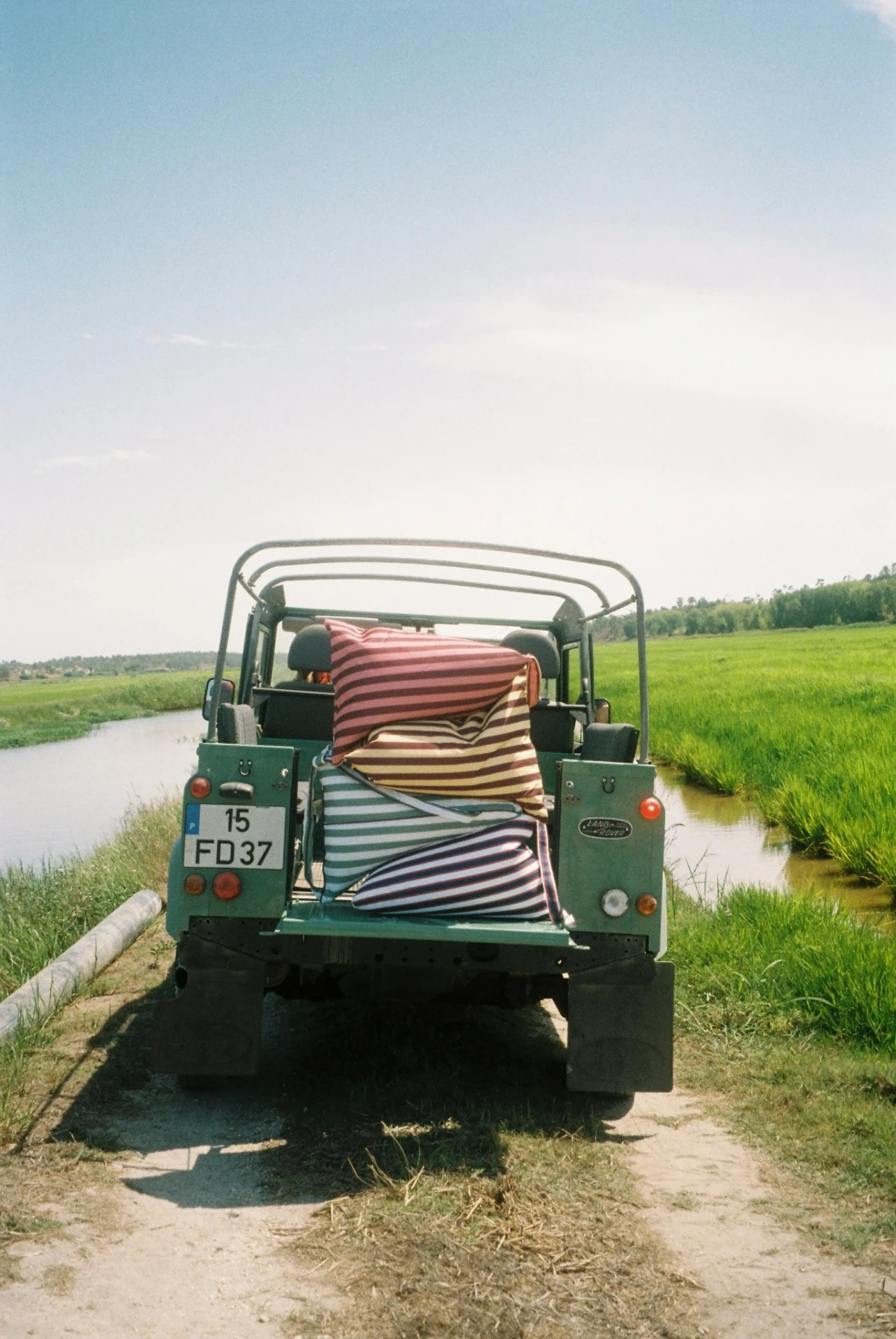 Striped LIELOW bags stacked in the back of a green Land Rover