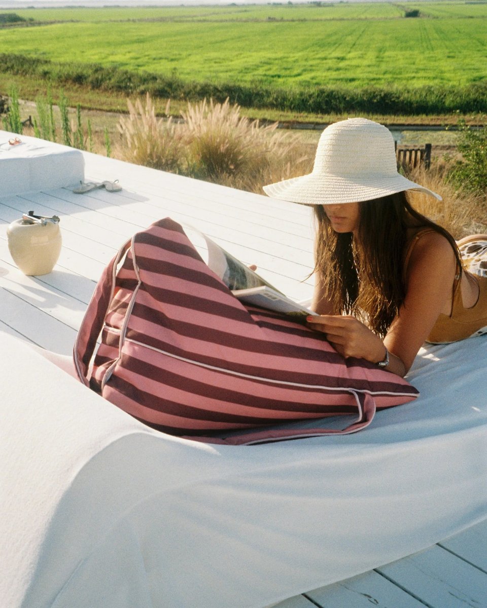 Woman reading on a deck, propped on the East Hampton backrest