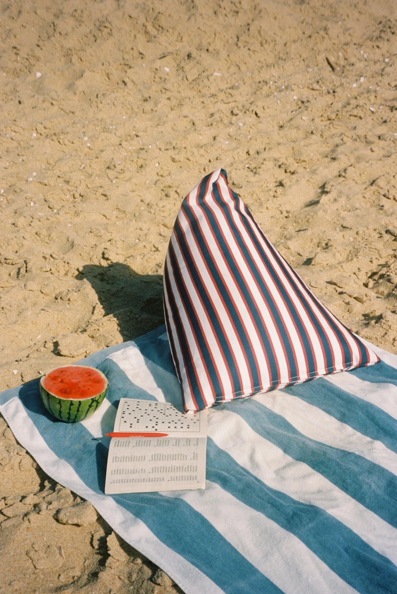 LIELOW Montauk — striped bag-chair upright on a beach towel beside a watermelon
