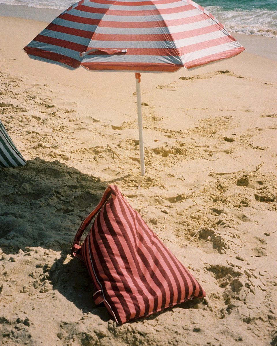 East Hampton backrest on the sand under a striped umbrella