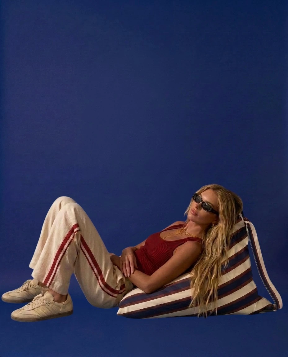 03 Sit — model lounging on LIELOW bag with magazine in park